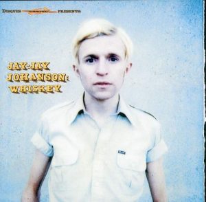 Pochette de l'album de Jay-Jay Johanson "Whiskey" (le chanteur se tient face à l'objectif, en chemise blanche à manches courtes sur un fond bleu)